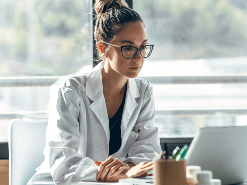 Nachdenkliche Apothekerin vor Computer